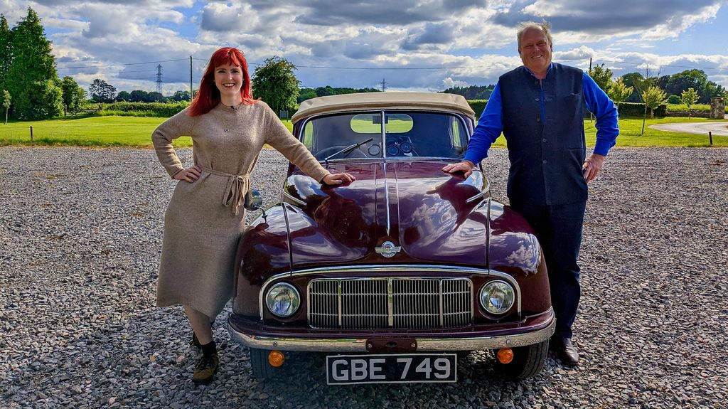 Man and woman standing either side of classic red car