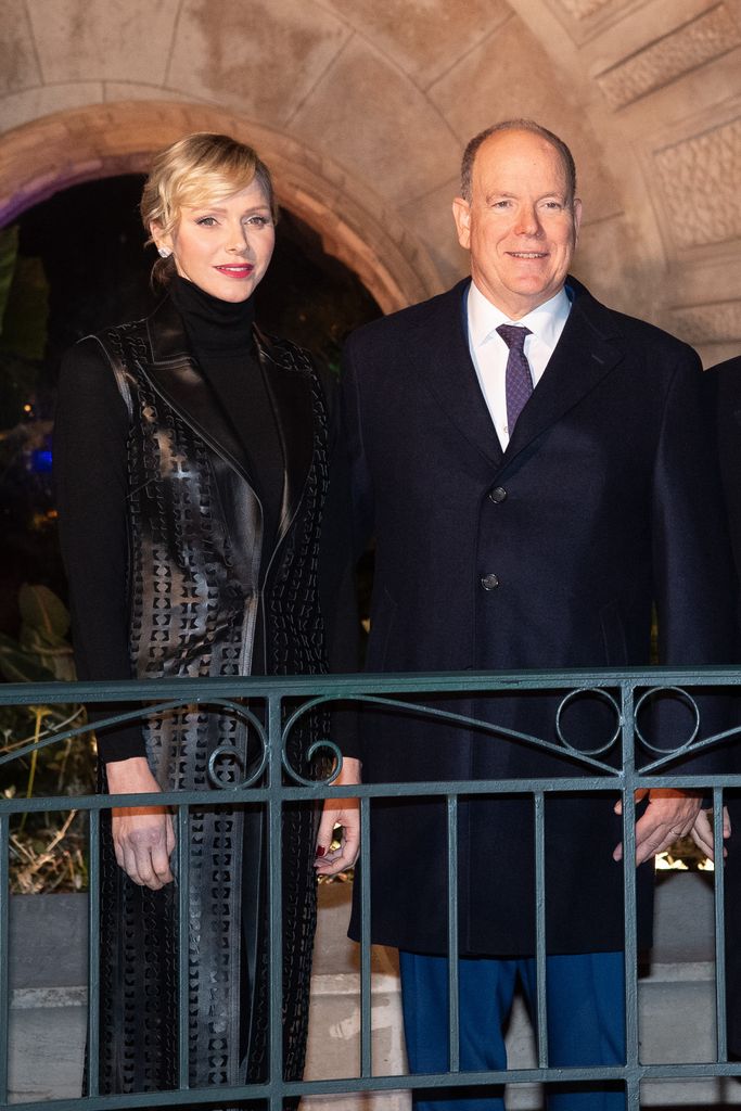 Princess Charlene in black cut out jacket and Prince Albert poses in suit