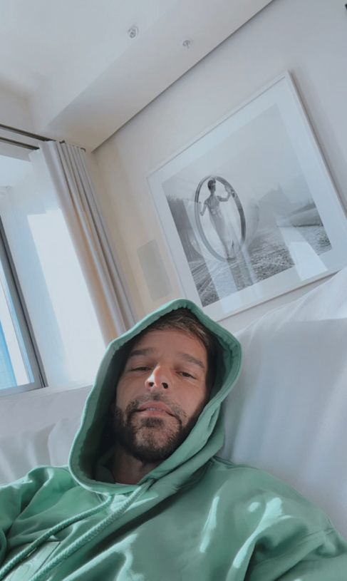 Ricky Martin in a green hoodie on a white sofa