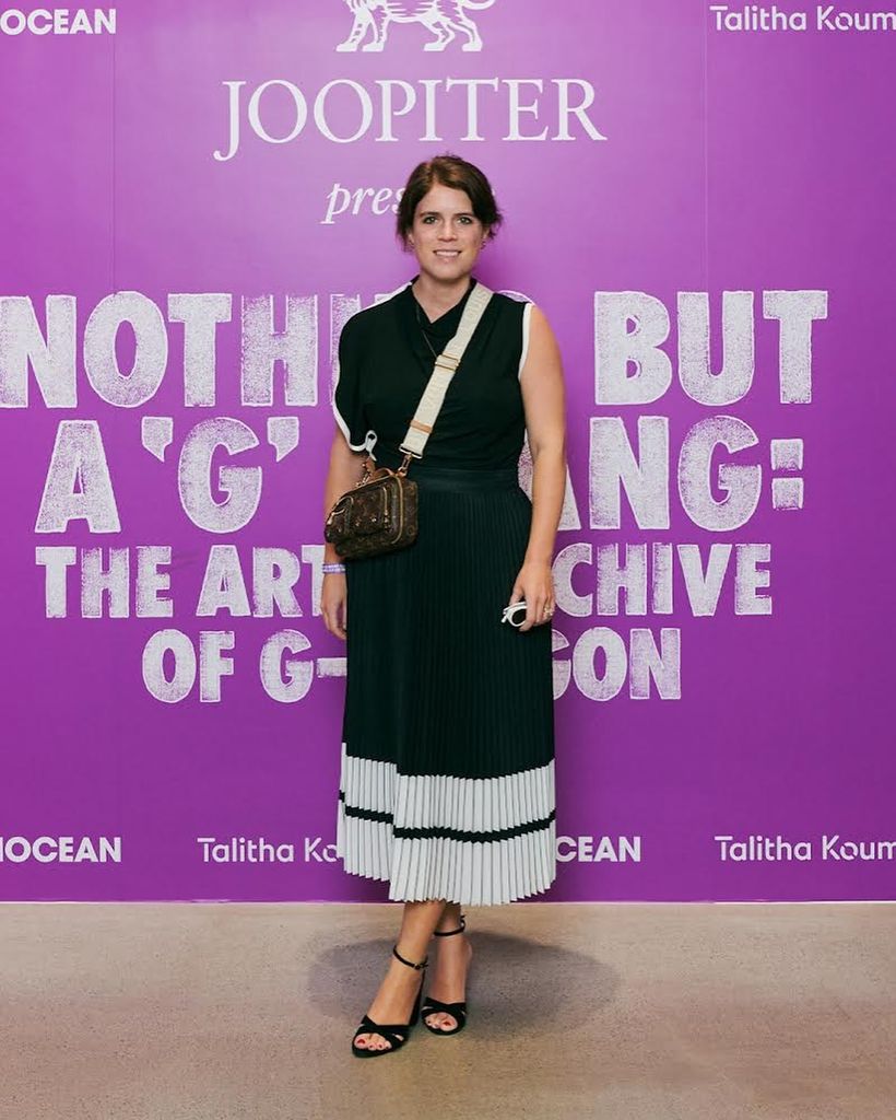 Princess Eugenie in a black skirt in front of a purple board