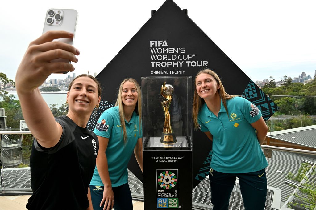 Australia's Sarah Hunter, Courtney Nevin, and Clare Hunt take selfies with the trophy for the Australia and New Zealand 2023 Women's World Cup football tournament 