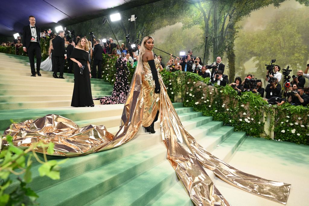Serena Williams on steps in gold trailing gown