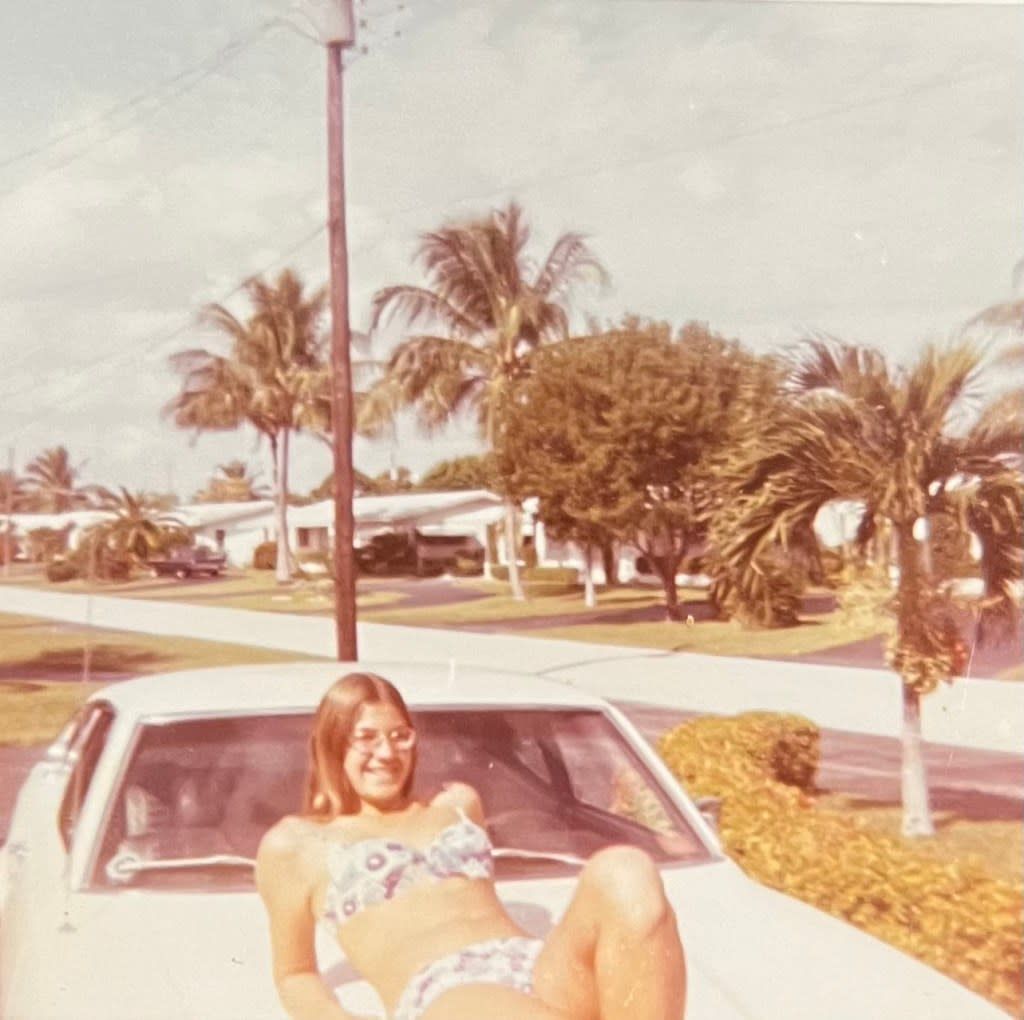 Karen Grammer poses in a bikini on the hood of a car in the early 1970s