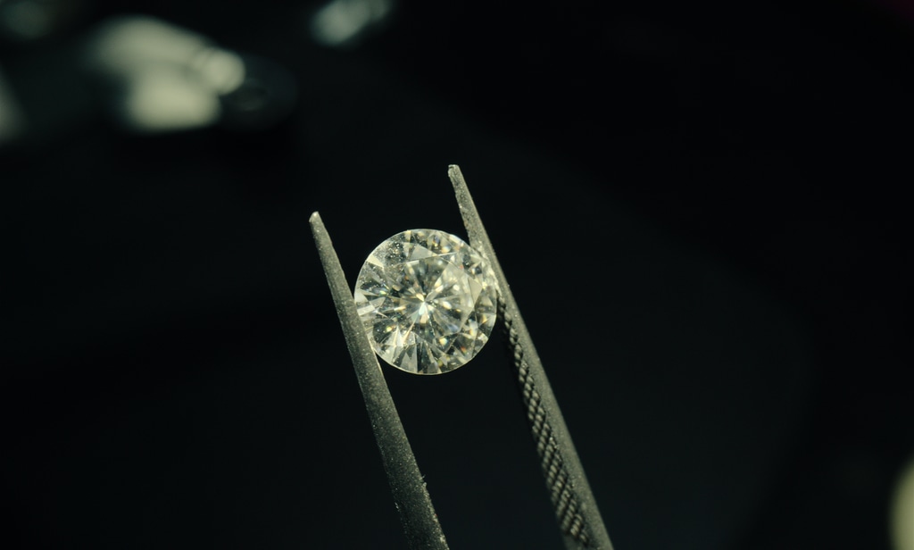 A diamond is examined with a tweezer