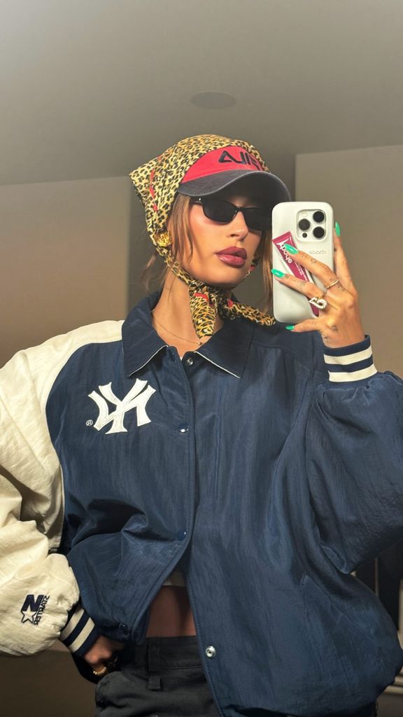 Hailey Bieber poses in a blue jacket, sunglasses, a cap and headscarf 