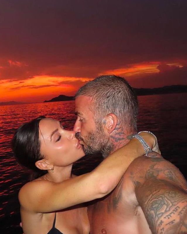 Victoria and David Beckham kissing against a sunset