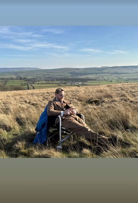 man sitting in chair in middle of field