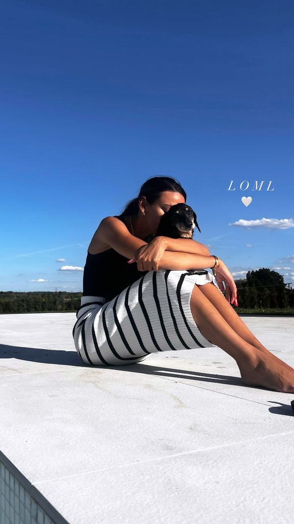 Michelle Keegan sitting in a striped skirt cuddling her dog