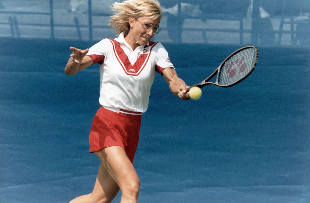 Martina Navratilova playing tennis in a white shirt and red shorts