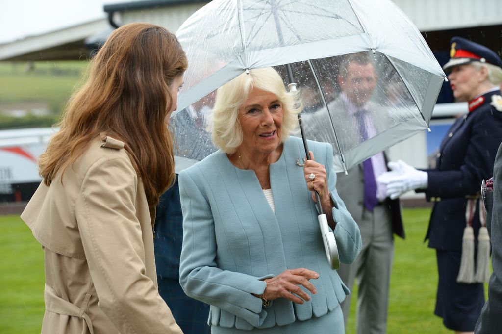 Queen Camilla in blue outfit holding umbrella at Hexham Racecourse