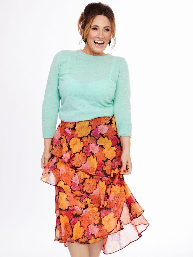 Grace Dent in a floral printed skirt and mint green top looking very happy