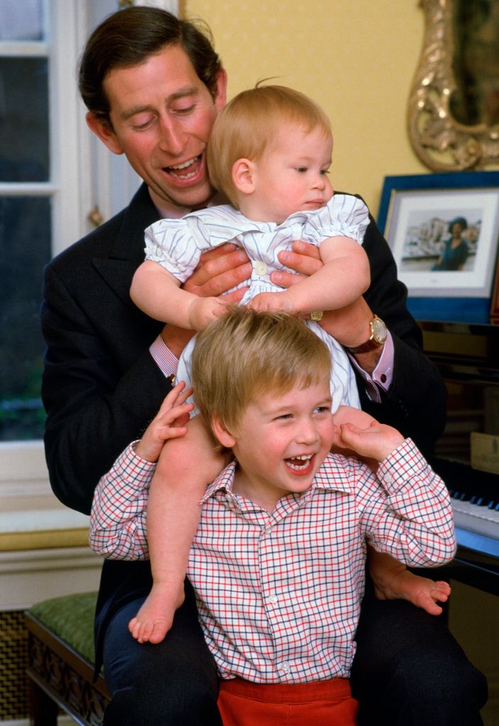 Charles lifting baby Harry onto Prince William's shoulders