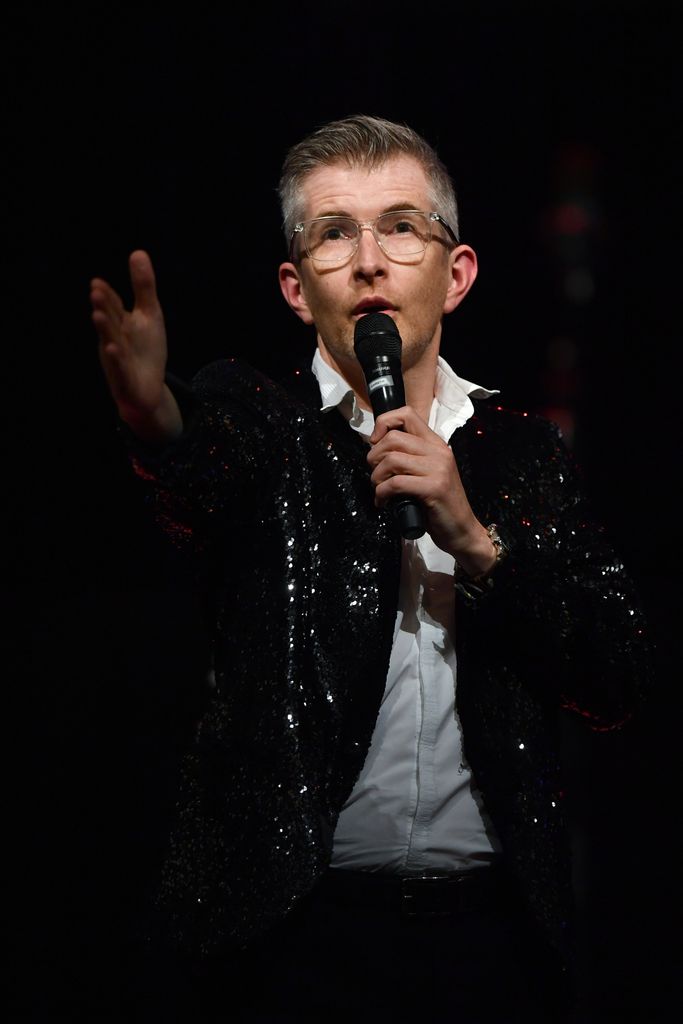 Gareth Malone holds microphone on stage in 2022