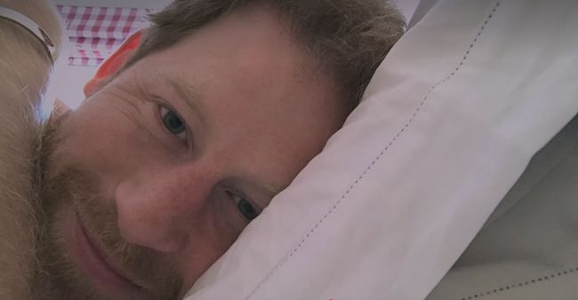 prince harry smiling with head on pillow 