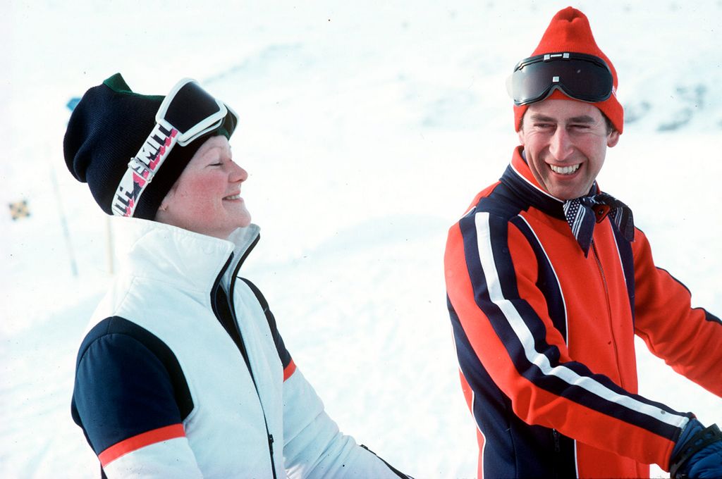 Lady Sarah Spencer dressed in a white ski suit laughing and Prince Charles in a red ski suit laughing at her