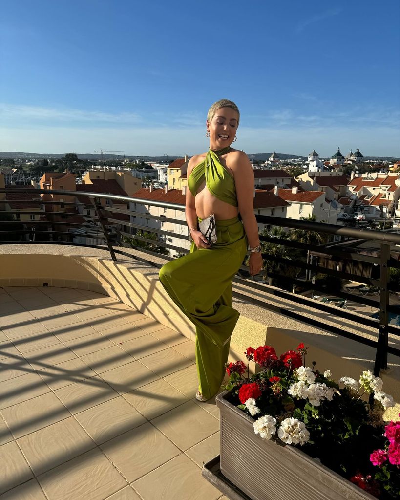 woman wearing green jumpsuit whilst posing on balcony