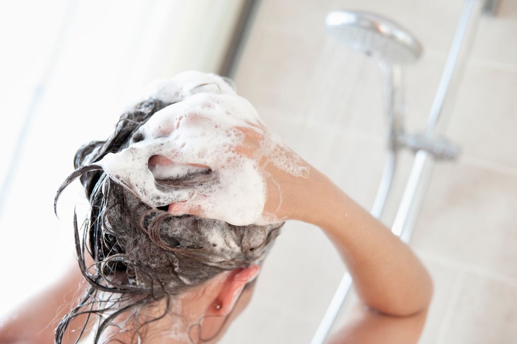 A woman taking a shower and washing her hair.