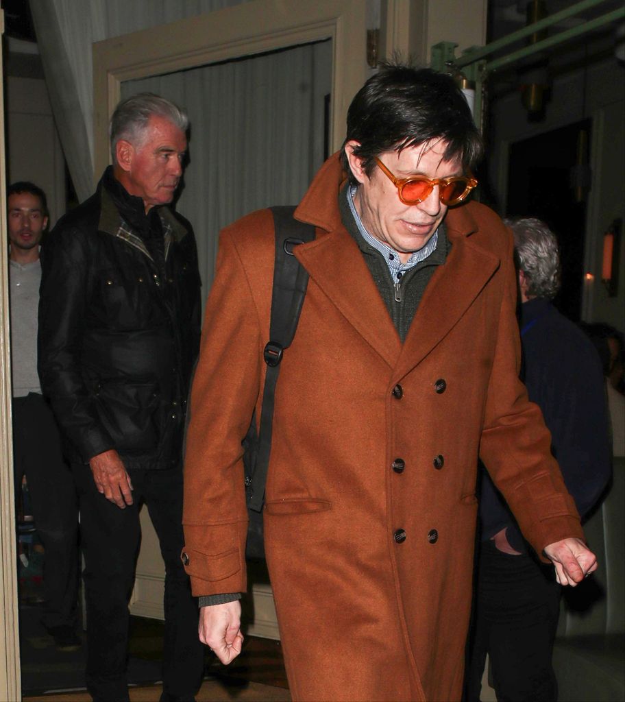 Pierce Brosnan in black jacket with adoptive son Christopher in brown trench