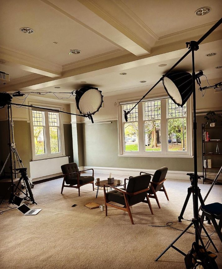 A room with wooden floor. Three chairs and studio lights are inside