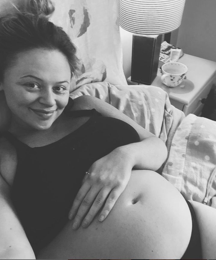 A pregnant Emily Atack in her underwear lying in bed