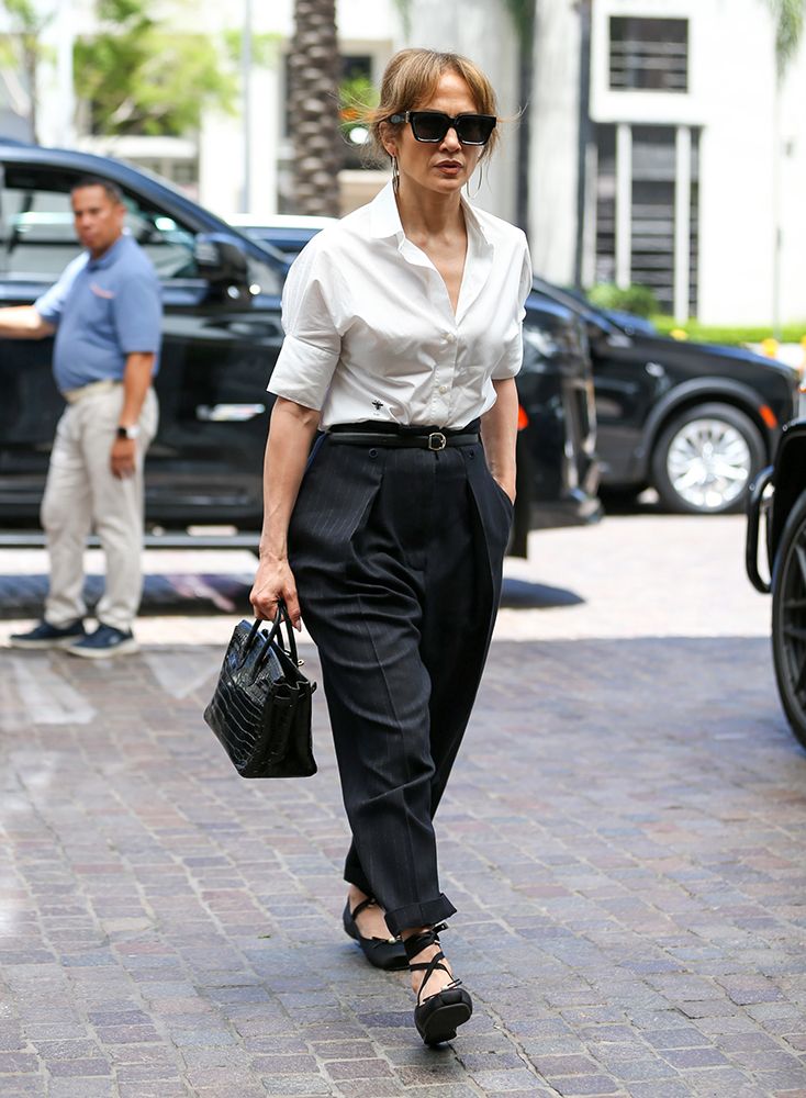 Jennifer Lopez wearing a black trousers, white shirt and ballet flats