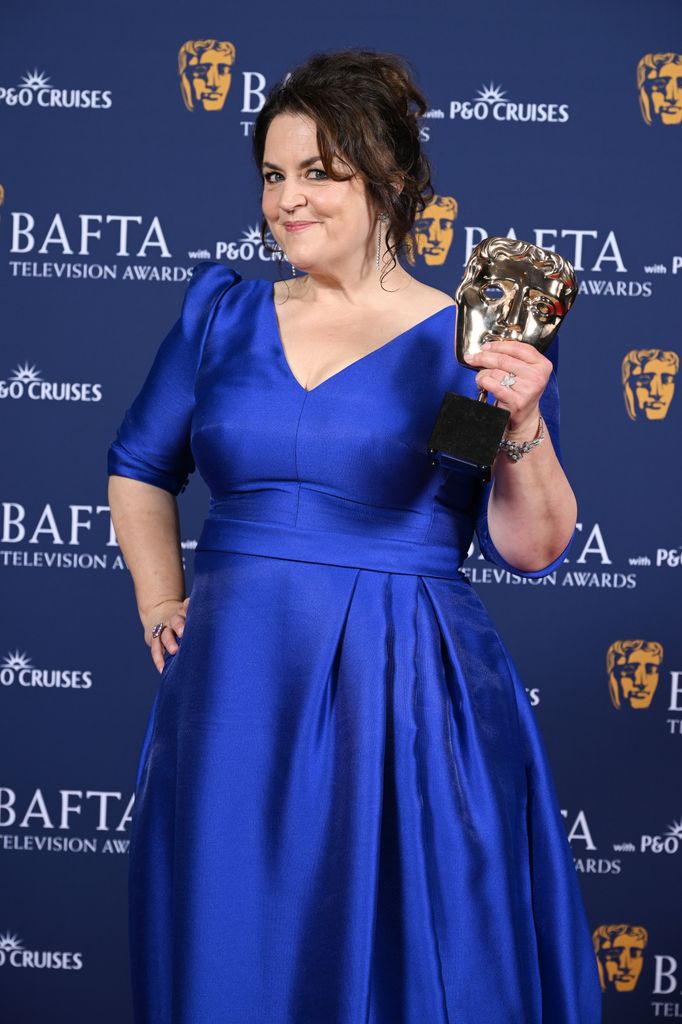 Ruth Jones in a blue dress holding a BAFTA award