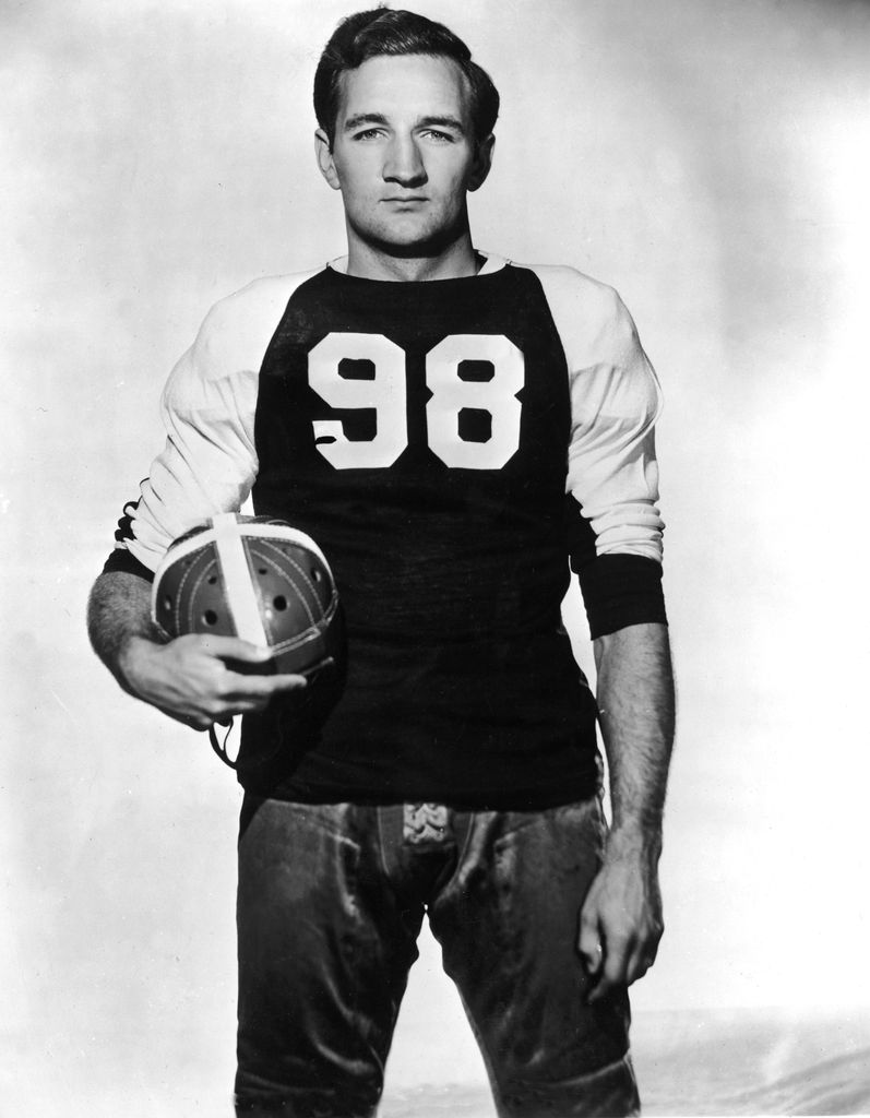 Circa 1945, Portrait of American football player Tom Harmon (1919 - 1990) holding a helmet while wearing a football jersey, Mark Harmon's dad