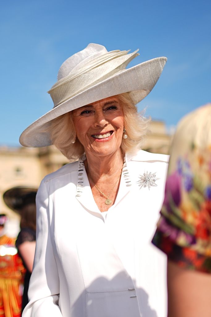 Queen Camilla smiling in a white outfit