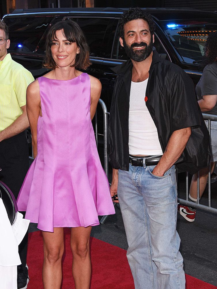 Rebecca Hall wearing a pink dress. Morgan Spector in a black shirt and blue jeans