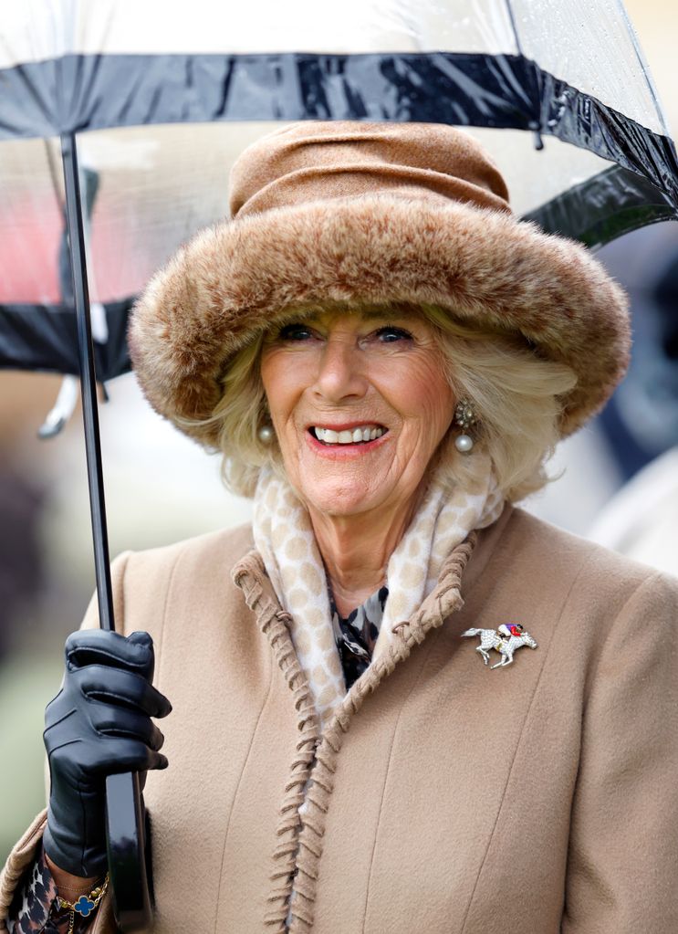 Queen Camilla smiling and holding an umbrella at Cheltenham Festival 2023