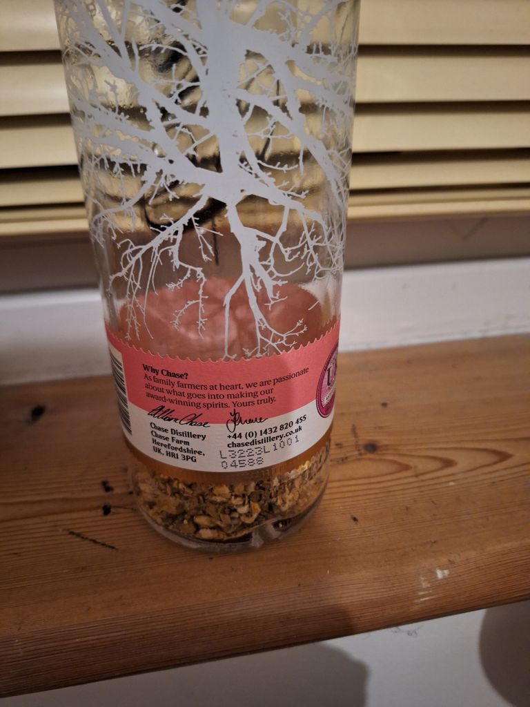 A bottle on a windowsill with pebbles inside