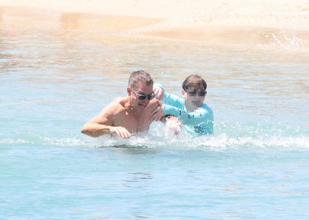 Matt Damon is pictured roughhousing with a young boy in the Greek waters