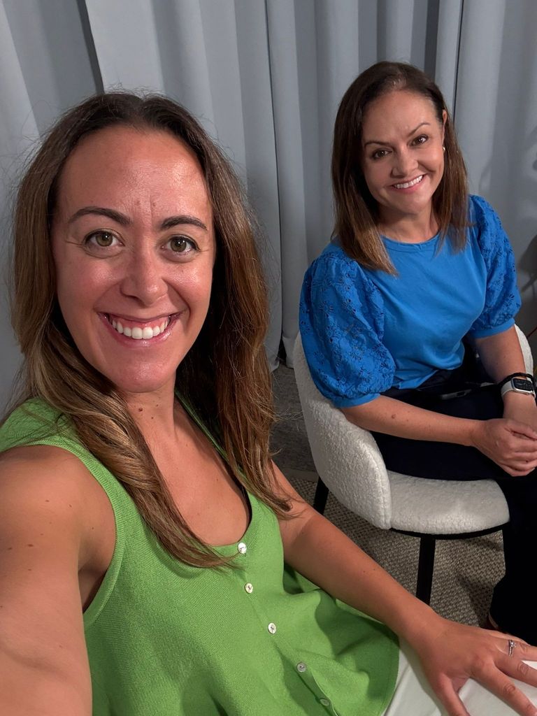 Andrea Caamano and Emily Nash grinning while sitting in chairs