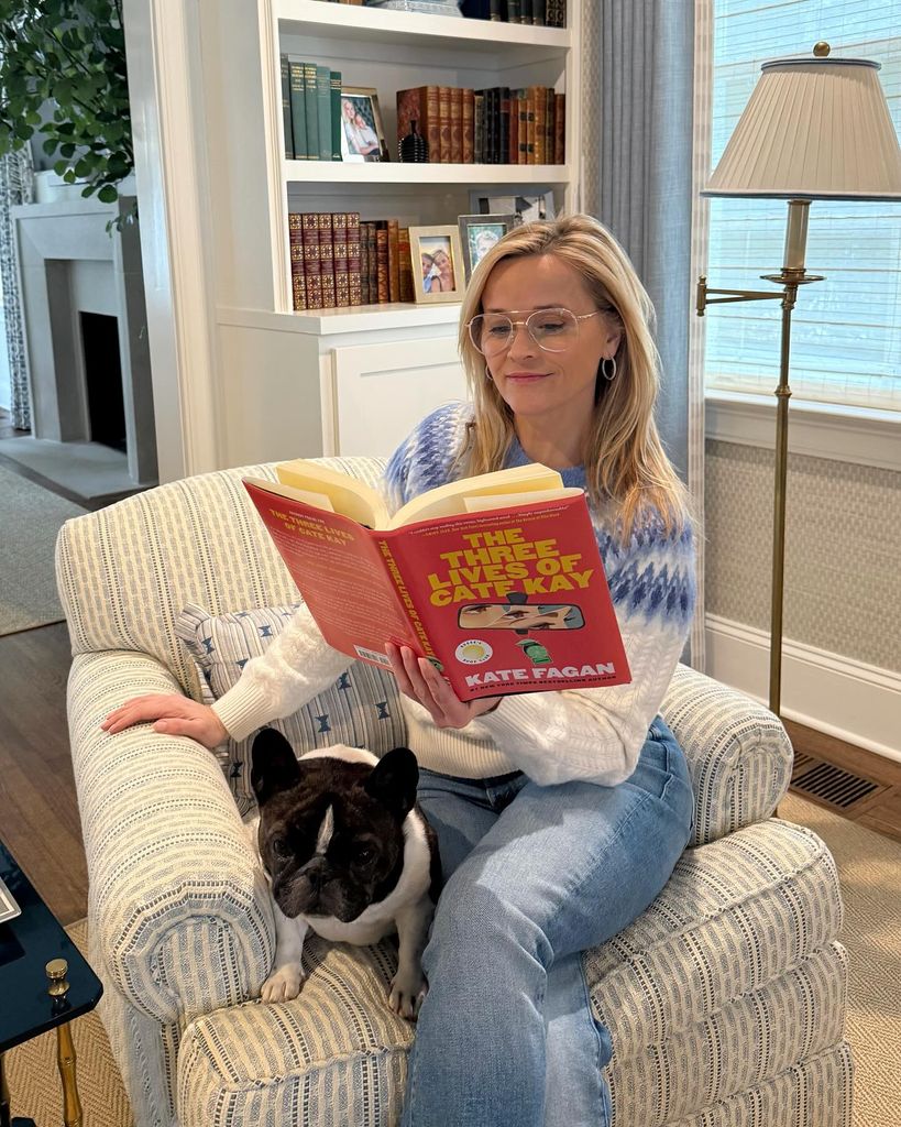 Reese reading book with dog on armchair