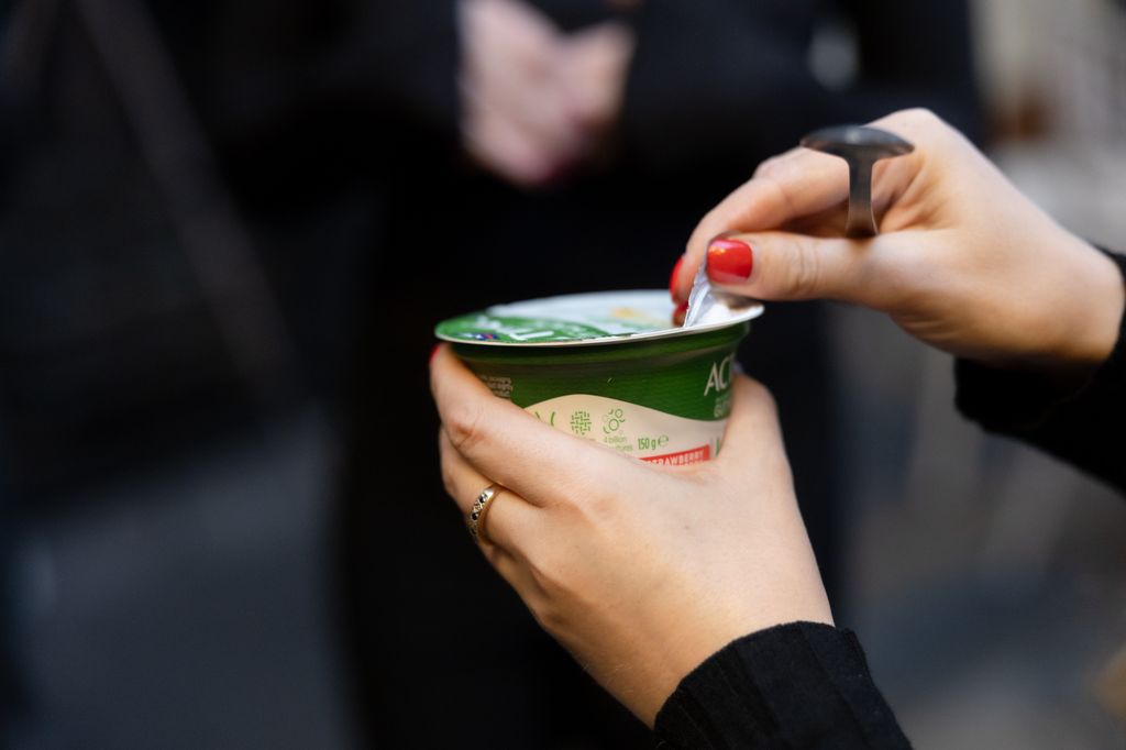 Woman with red nails opening an Activia yogurt