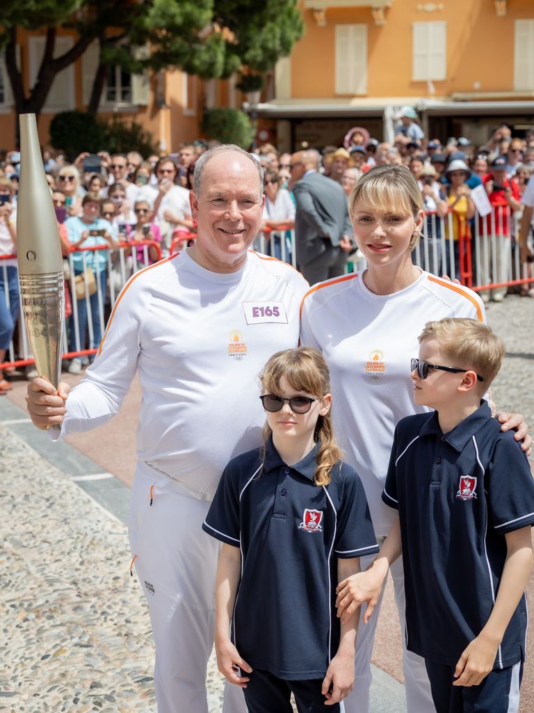 Prince Albert holding the Olympic torch alongside Princess Charlene, Prince Jacques and Princess Gabriella