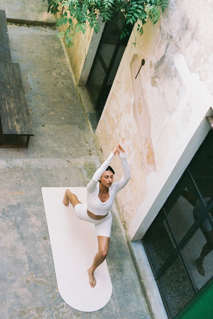 woman doing yoga in white set from birdseye view