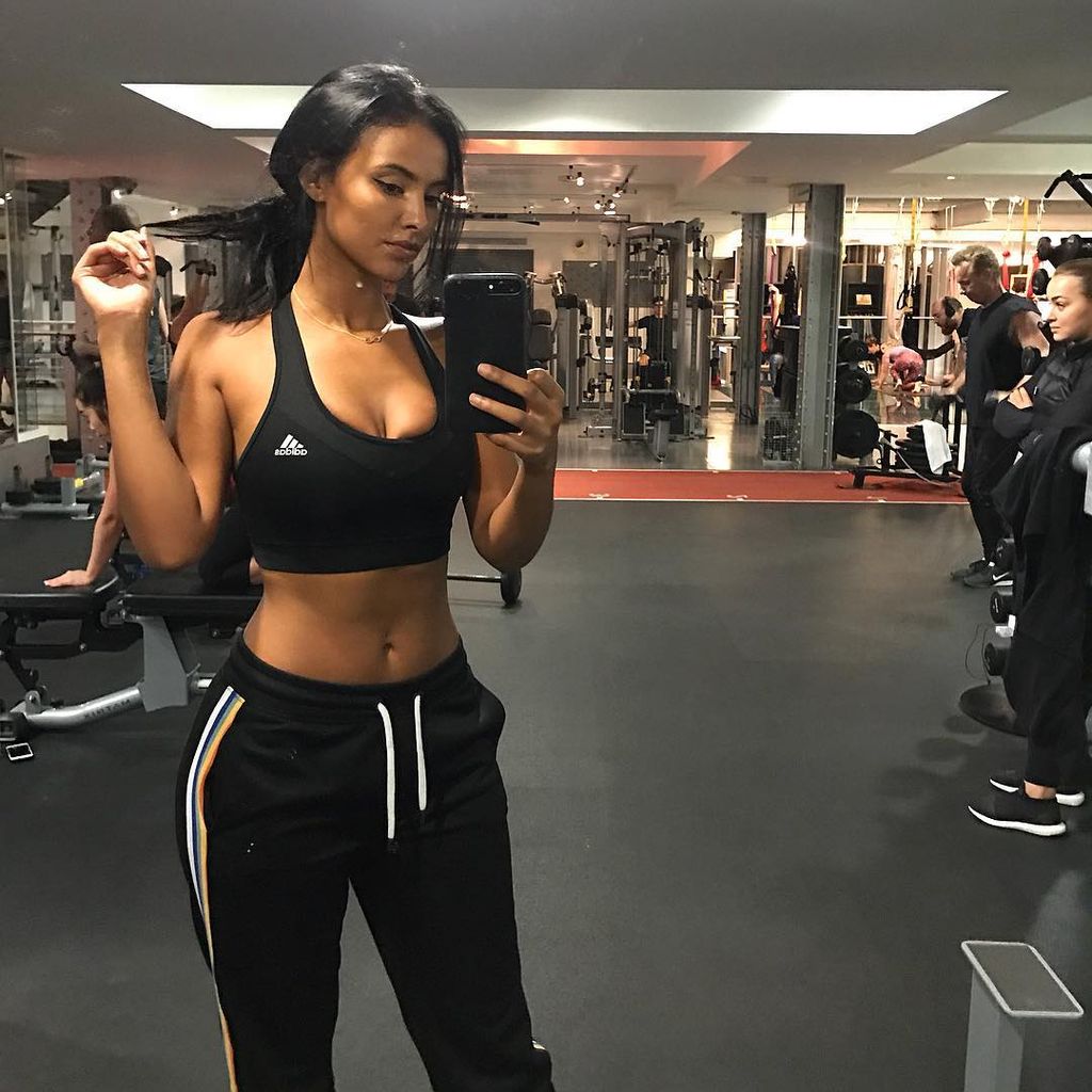 Maya posing for a mirror selfie in the gym 