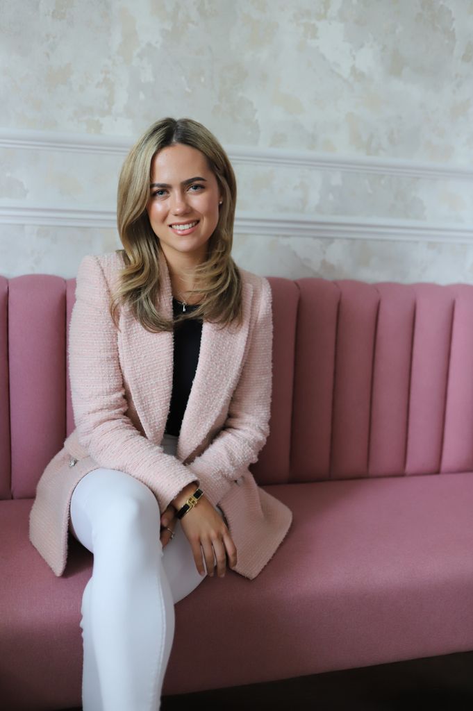 Beautiful blonde woman sitting on a pink sofa in pink blazer 