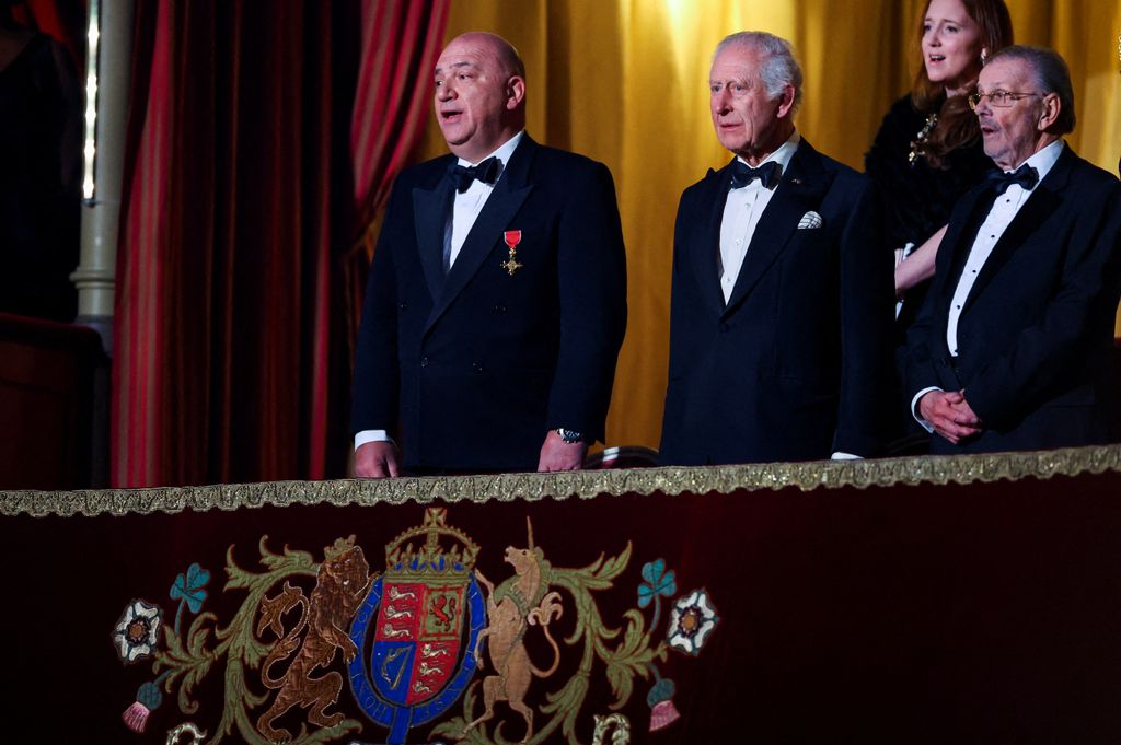 Britain's King Charles III (3R) stands with Giles Cooper, chair of the Royal Variety Charity, as the national anthem is played