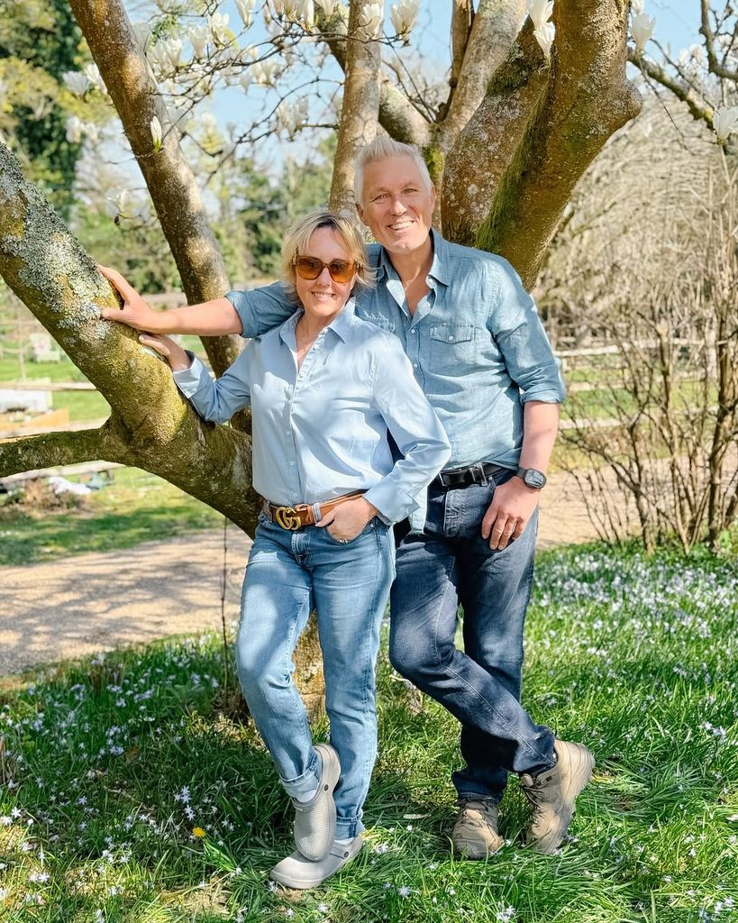 Martin and Shirlie Kemp stand side by side wearing matching denim in front of a tree in their garden at home
