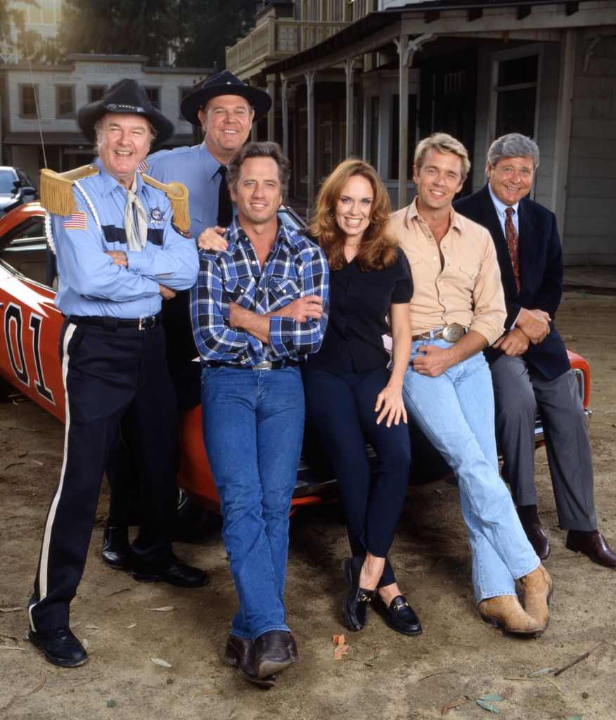 Pictured from left is James Best (as Rosco P. Coltrane), Rick Hurst (as Deputy Cletus Hogg),Tom Wopat (as Luke Duke), Catherine Bach (as Daisy Duke), John Schneider (as Bo Duke),  Ben Jones (as Cooter Davenport) 