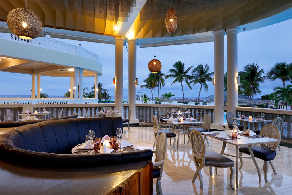 reaturant with tables, chairs and booths with palm trees in background