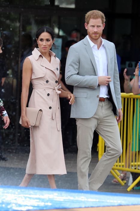 Prince Harry and Meghan Markle walking outdoors in formal wear looking worried