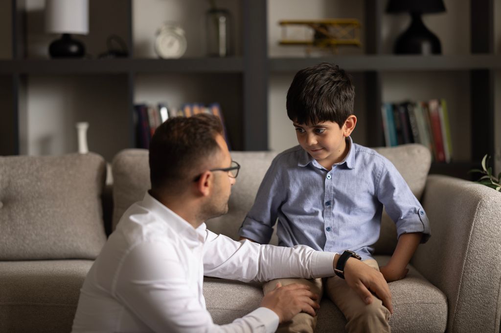 father talking to son on sofa