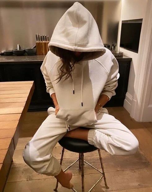 Victoria Beckham sitting on a stool in her kitchen with her hood up