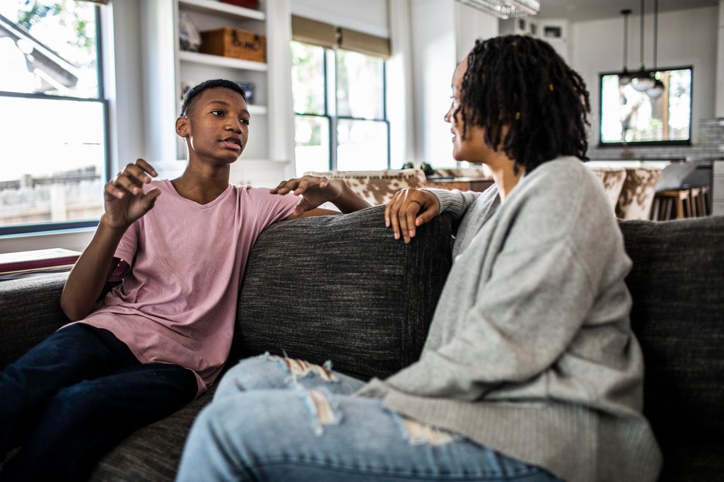 Mother and son having conversation on sofa at home