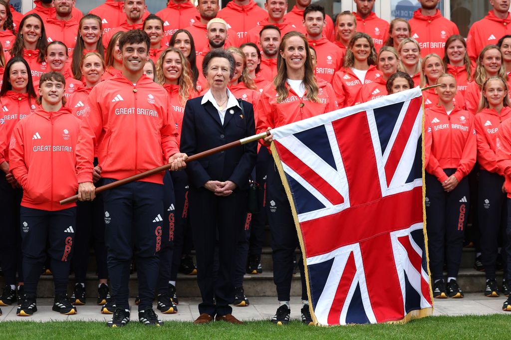 Princesa Anne posando com a Equipe GB e uma bandeira gigante