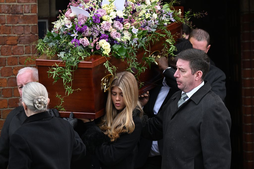 Darcey carries her father's coffin as she departs the funeral