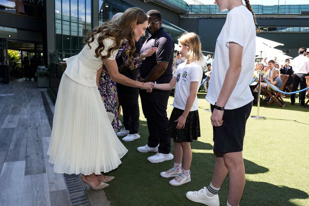 Britain's Catherine, Princess of Wales (L) Lydia Lowe, eight, from the Dan Maskell Tennis Trust, upon her arrival to attend the women's singles final tennis match on the thirteenth day of the 2025 Wimbledon Championships 